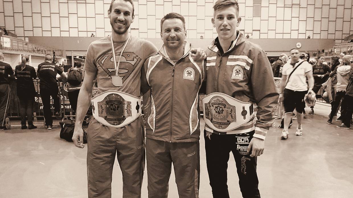 Dva tekmovalca Kluba Center s prvaškima pasovoma Kickboxing World Cup ob glavnem trenerju Igorju Paceku.